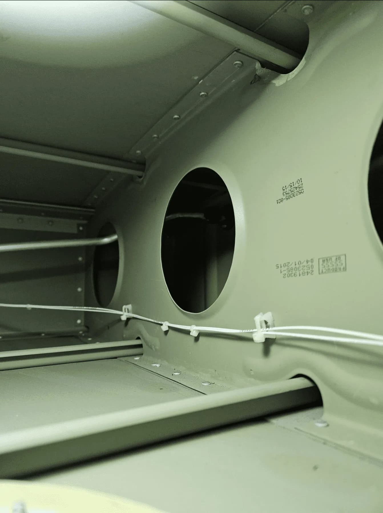 An internal view of an aircraft's structural framework with circular cutouts and wiring.