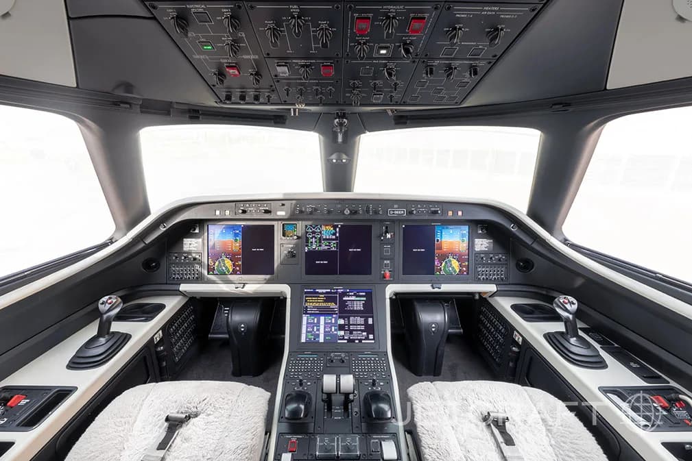 The cockpit of a jet aircraft with multiple display screens and controls.