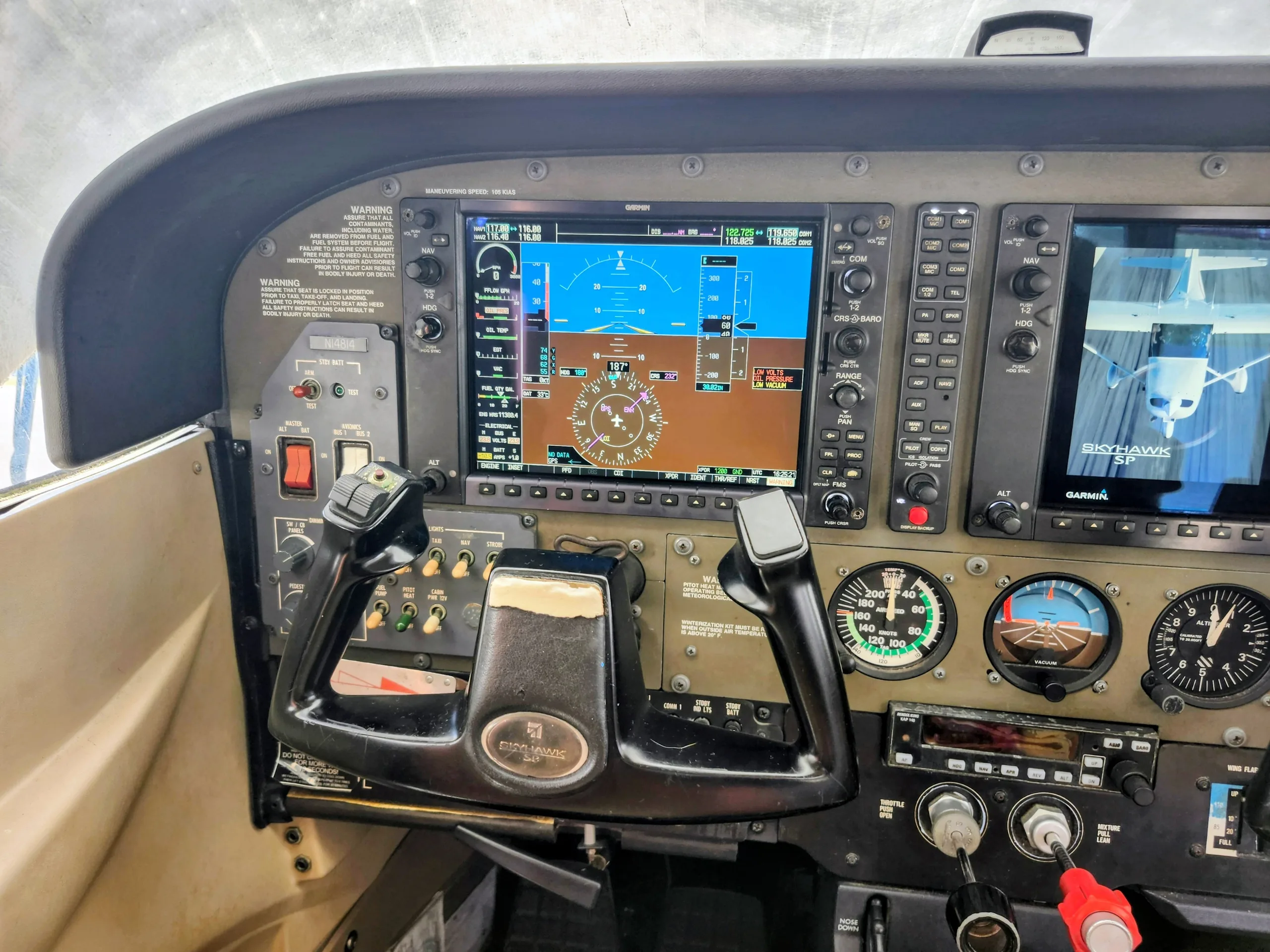 The left side of a Cessna Skyhawk SP cockpit shows the pilot's yoke and a Garmin G1000 display.