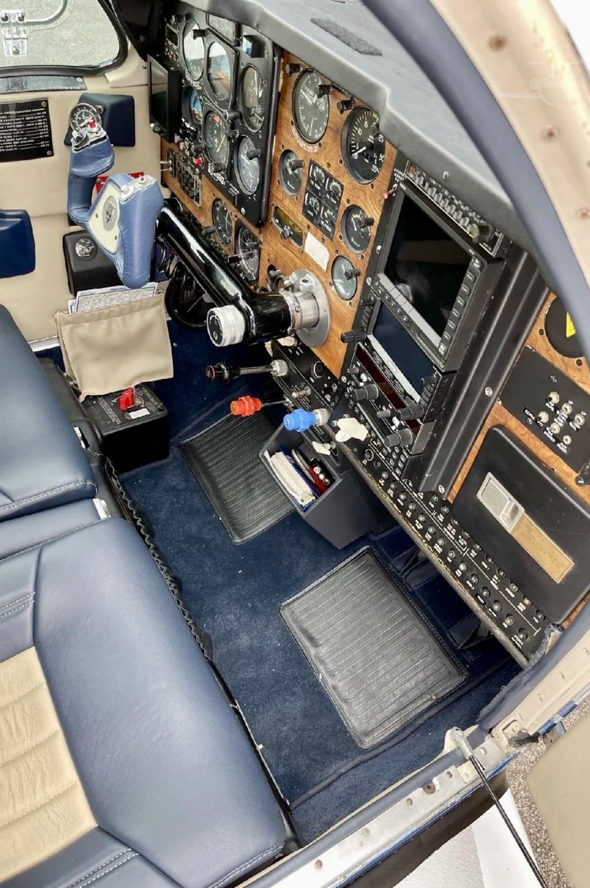 View of the aircraft's cockpit with a wood-paneled instrument panel and blue leather seats.