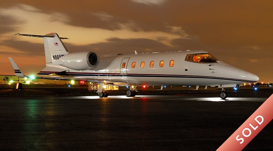 A Learjet 45XR on the tarmac at night, with a SOLD banner overlay.