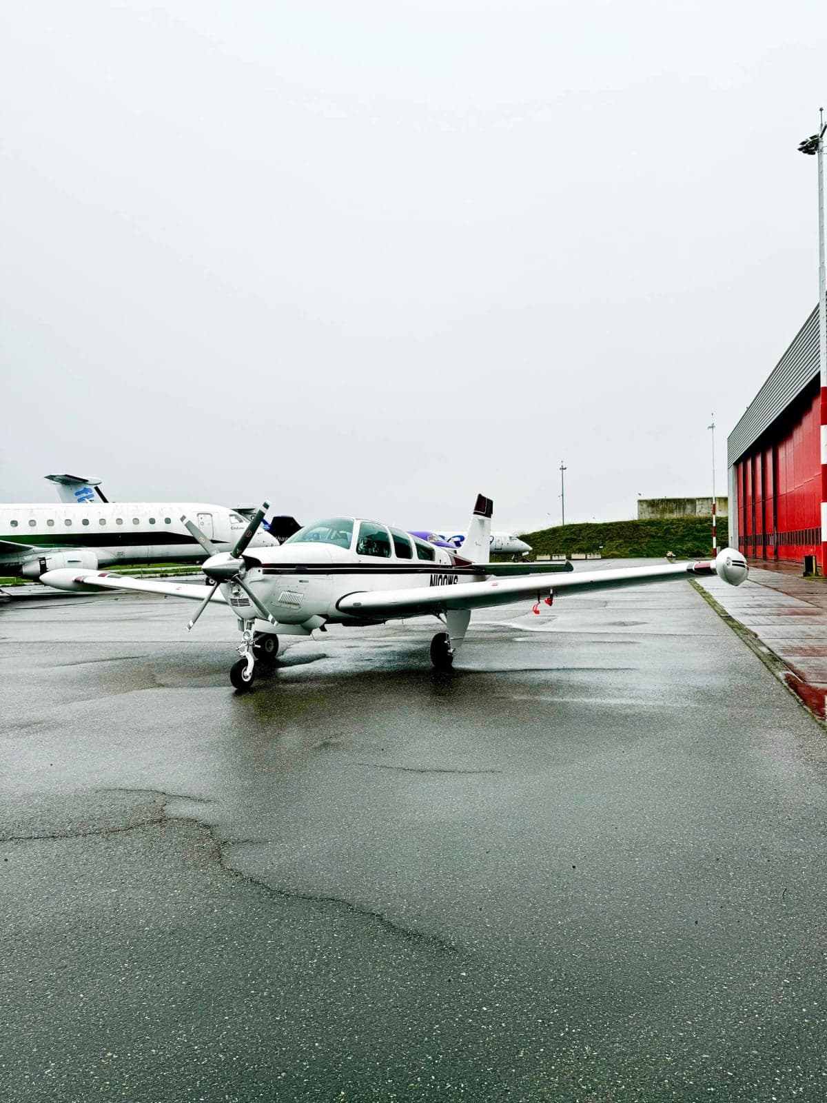 N100WS Bonanza aircraft parked on the tarmac with other aircraft in the background.