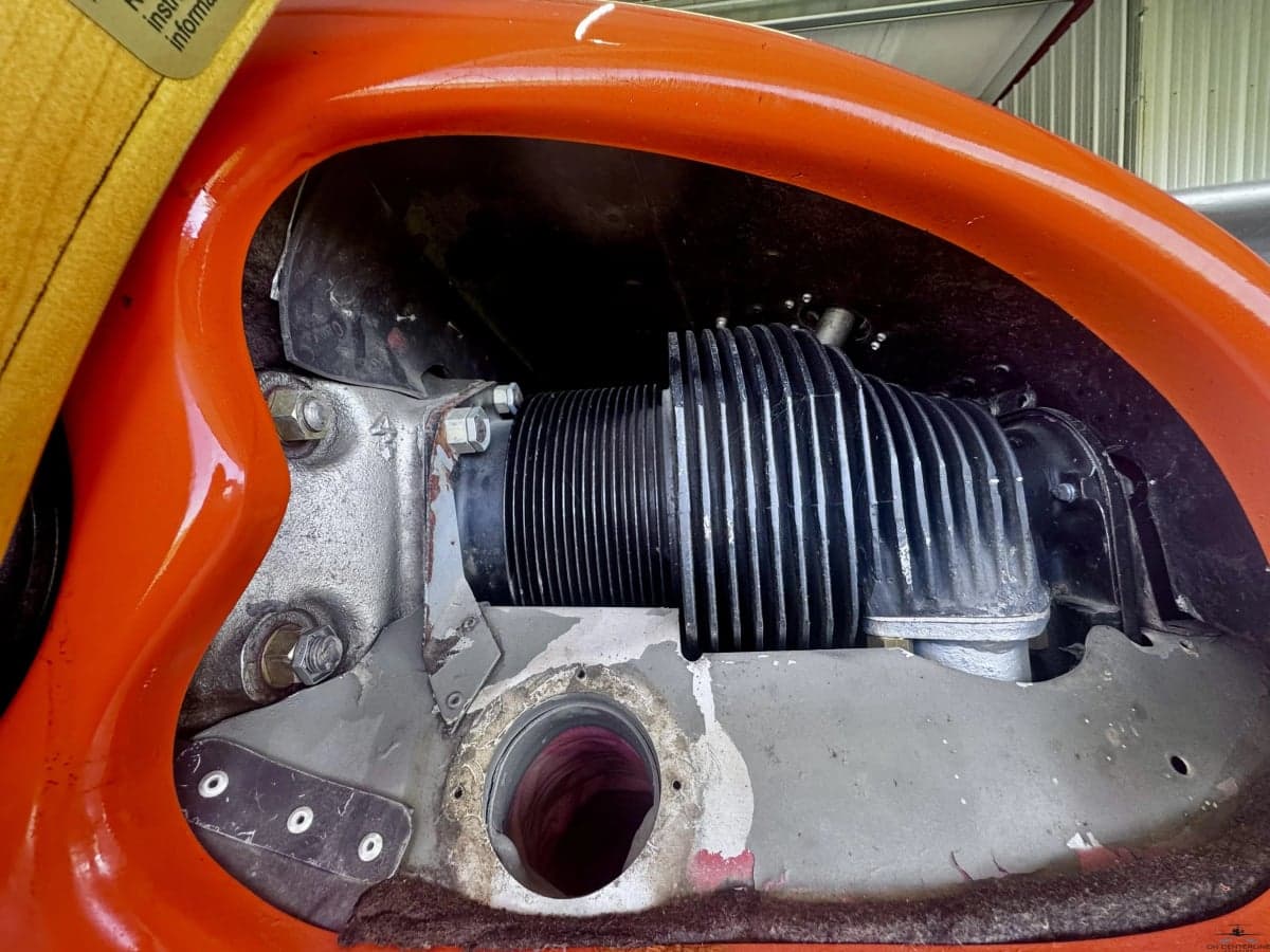 A close-up view of the engine cylinders and components inside the orange aircraft's cowling.