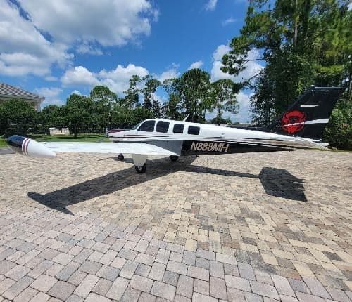 A Beechcraft Bonanza with registration N888MH is parked on a brick driveway, side view.