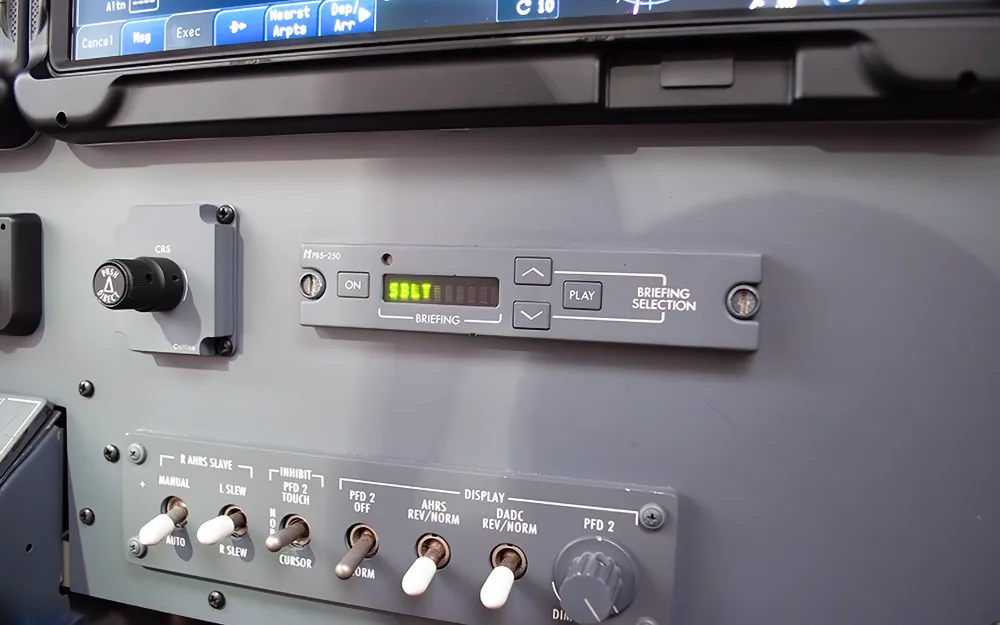 A close-up of a control panel in an aircraft cockpit, showing various switches and a digital display.