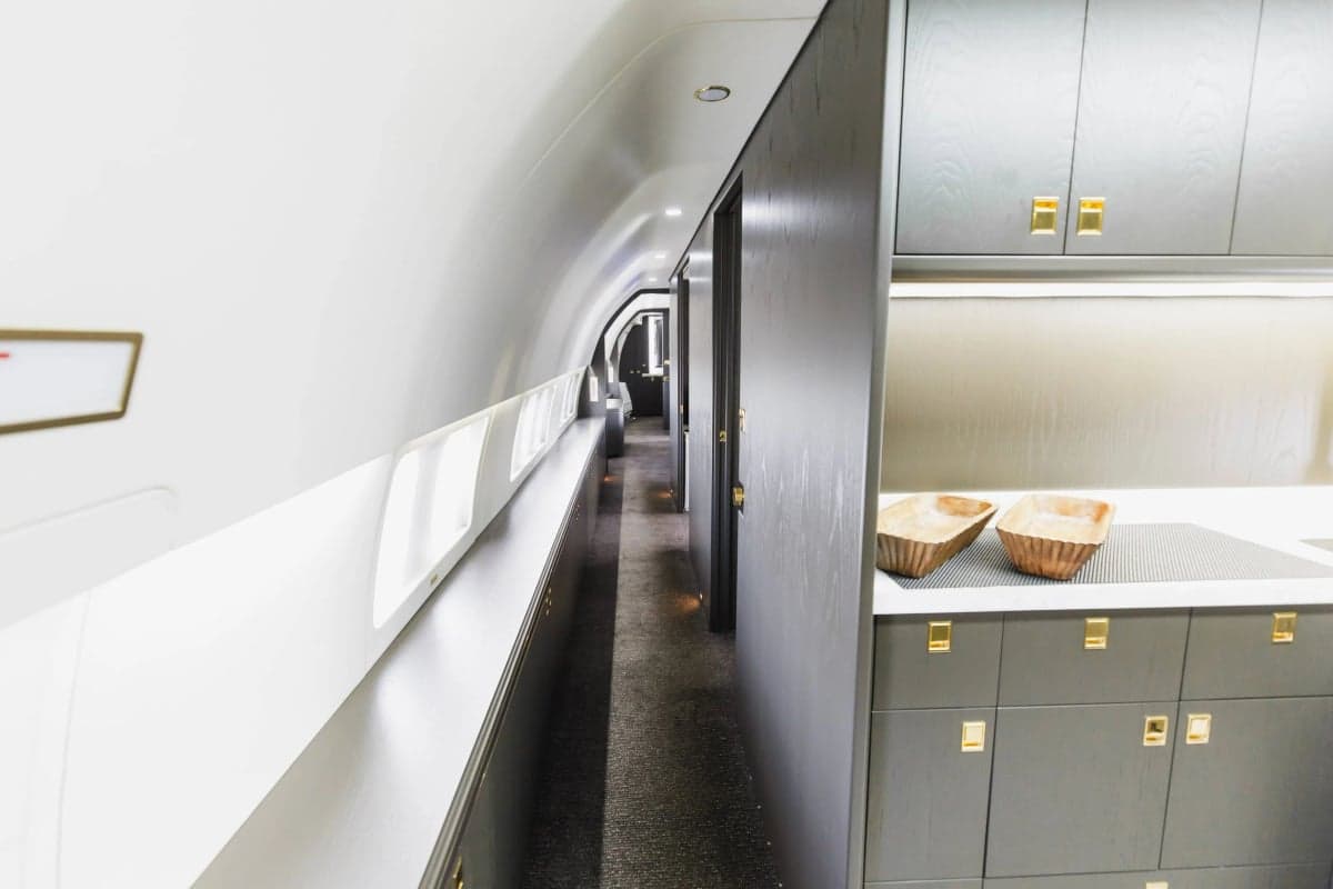 Hallway view of the aircraft's interior with dark wood cabinets and white walls.