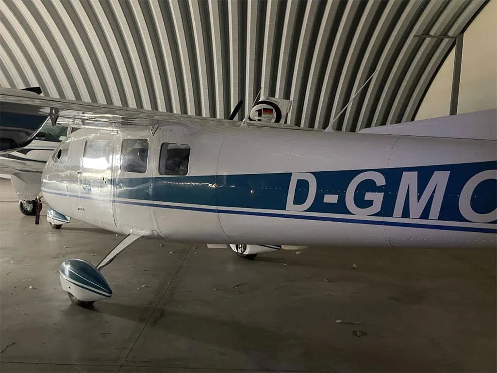 The fuselage of a white and blue Partenavia P.68 aircraft with registration D-GMC (partially visible) inside a hangar.