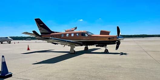 Pilatus PC-12 aircraft N970TB on the tarmac with a copper and black paint scheme.