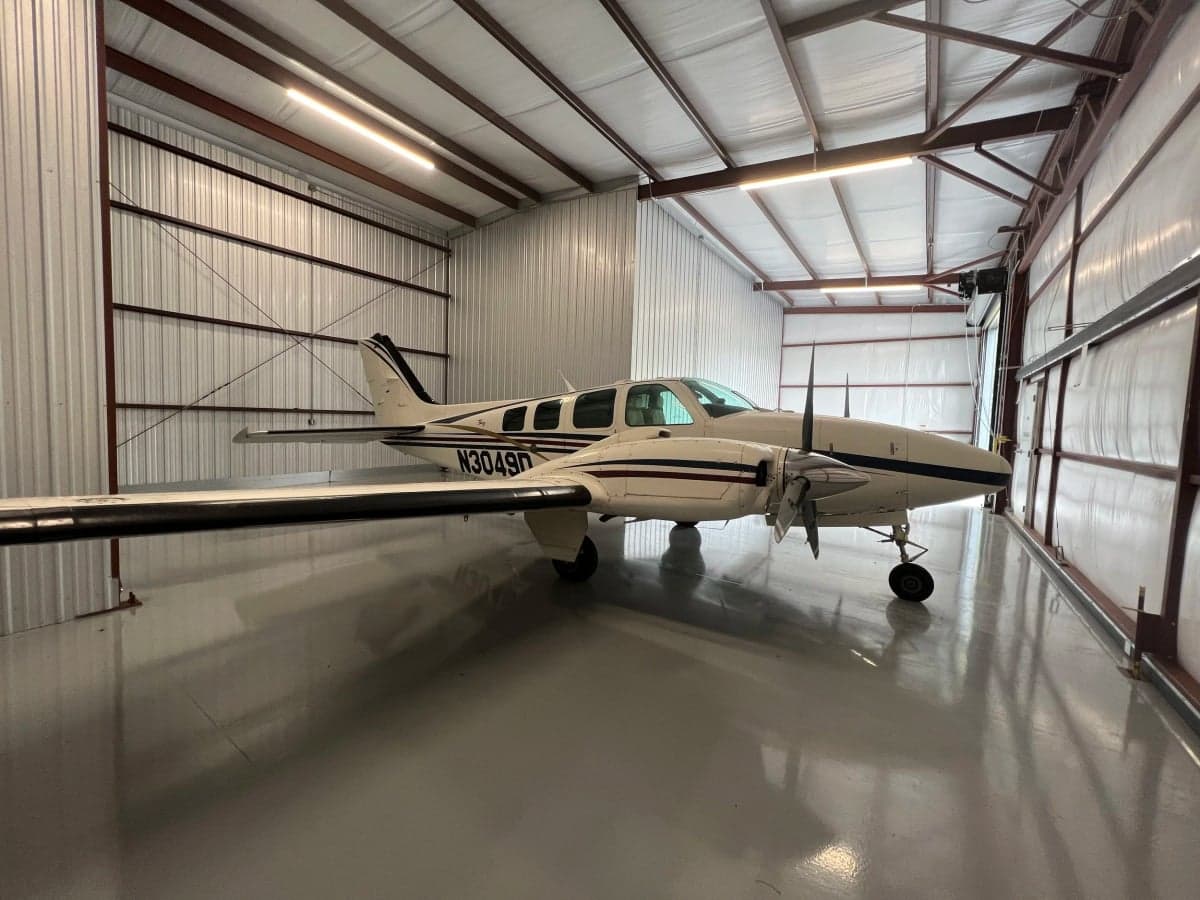A Beechcraft Baron aircraft with registration N3049D is parked inside a hangar.