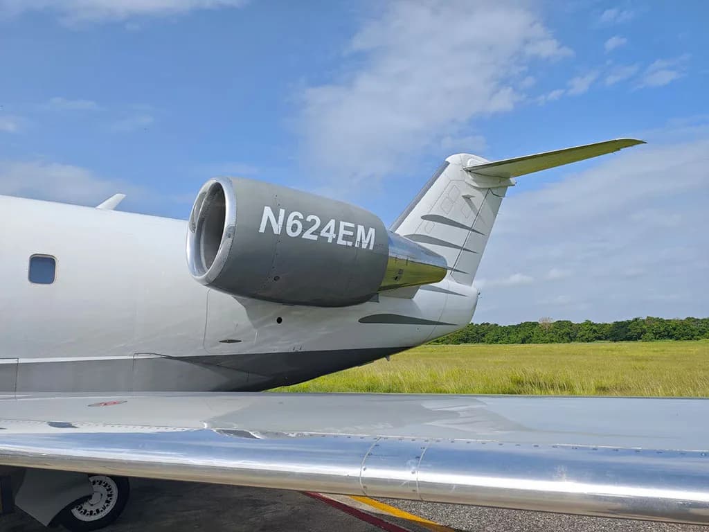 A close-up view of the engine and tail of the Bombardier Challenger 604 business jet, showing the registration N624EM.