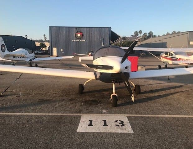 Front view of the Sling LSA aircraft parked on the tarmac in front of a hangar.
