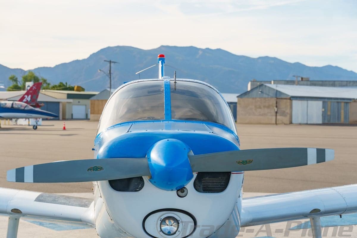 A head-on view of the blue and white single-engine aircraft N8718N, showing its propeller and nose cone.