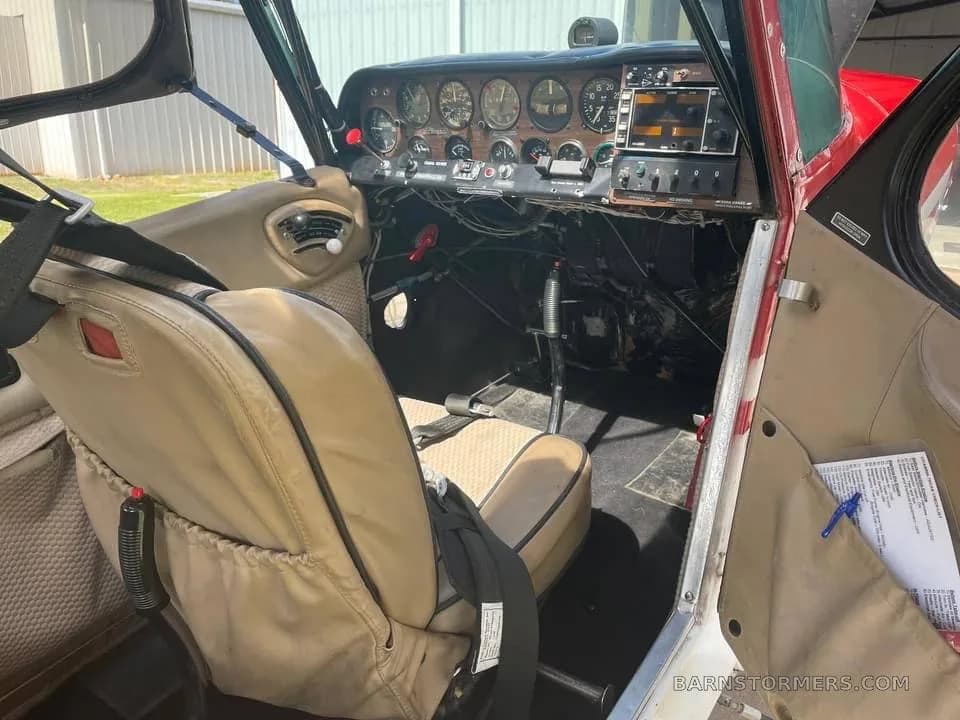 The cockpit of a small aircraft, showing the instrument panel and a tan pilot's seat.