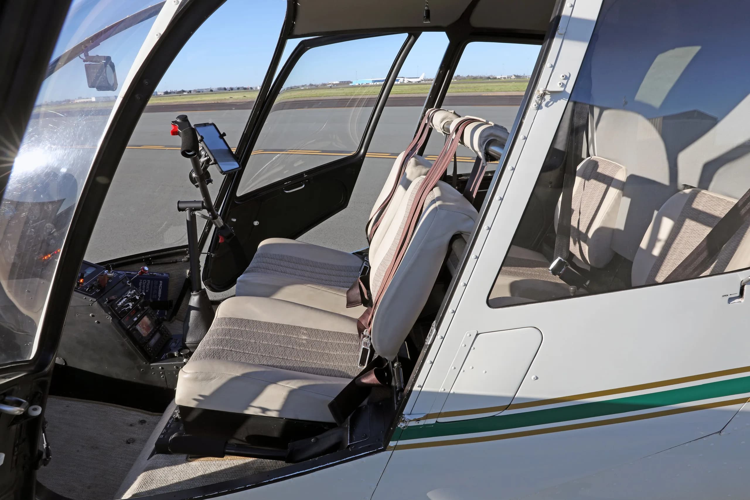 Interior view of the Robinson R44 Raven II helicopter cabin with beige seats and an open door.