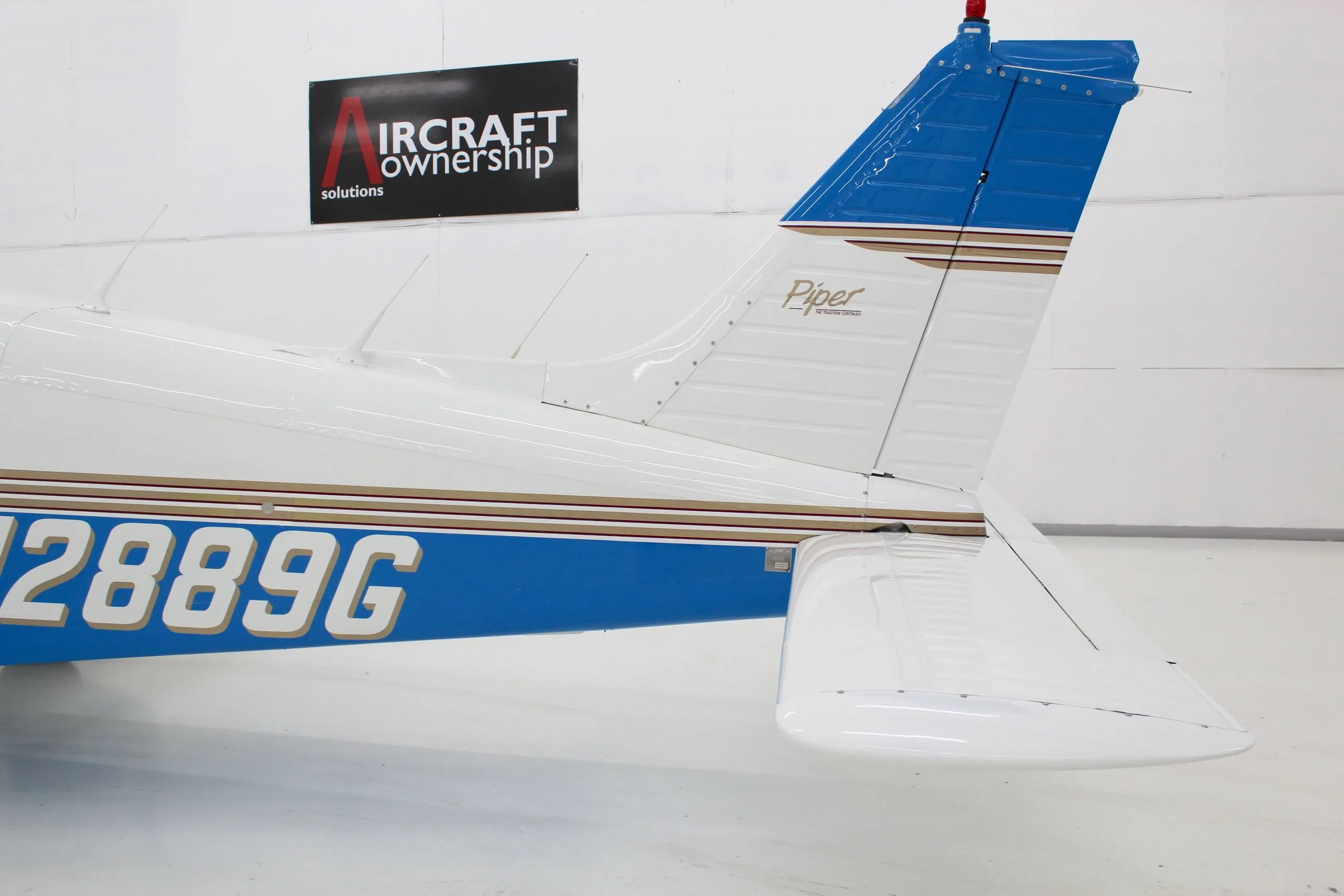 A close-up view of the tail section of the white and blue Piper Dakota aircraft, showing the Piper logo.