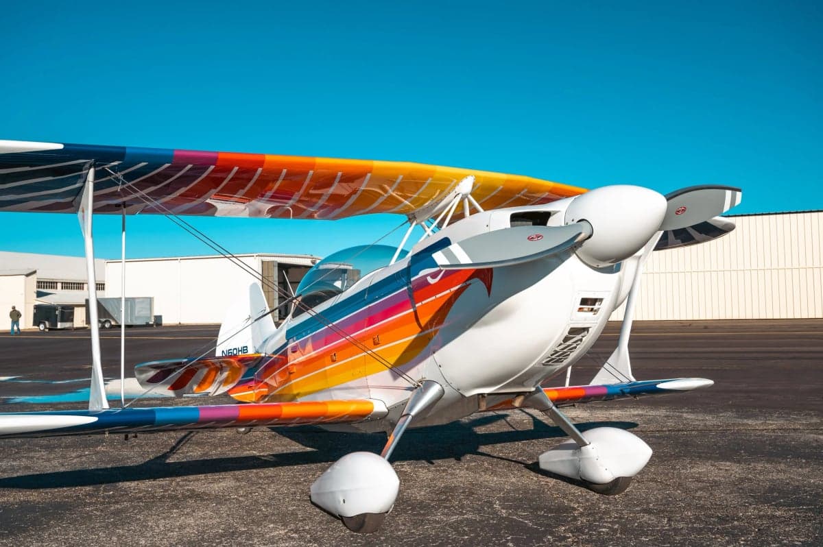 Front view of the Christen Eagle II biplane with a colorful paint scheme parked on the tarmac.