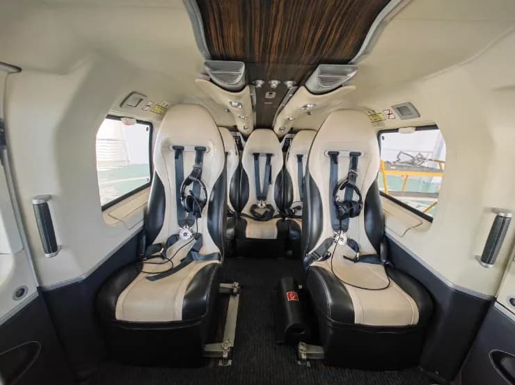 The interior of the helicopter features black and white leather seats with headsets.