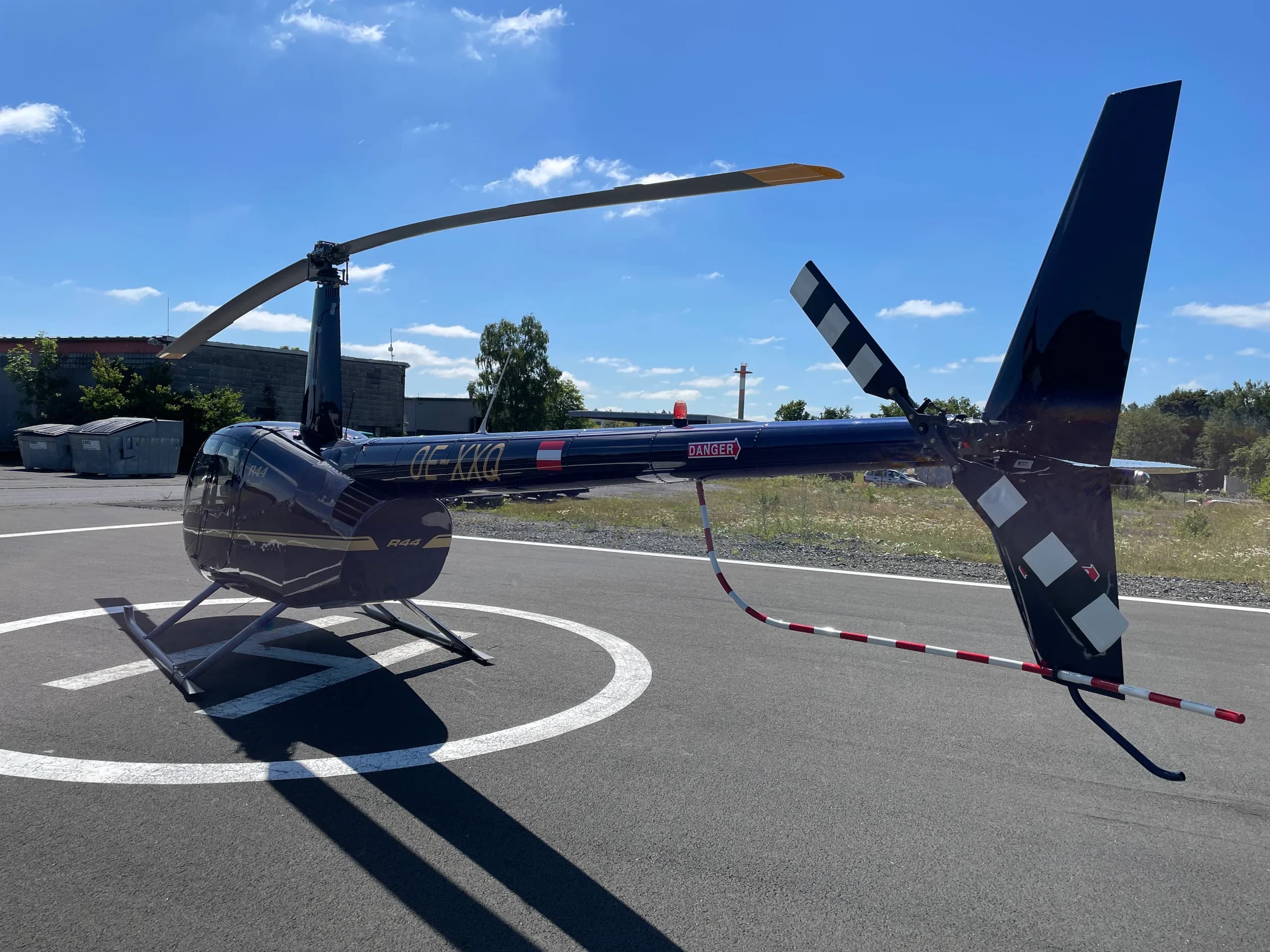 Robinson R44 Raven I OE-XXQ helicopter on a helipad.