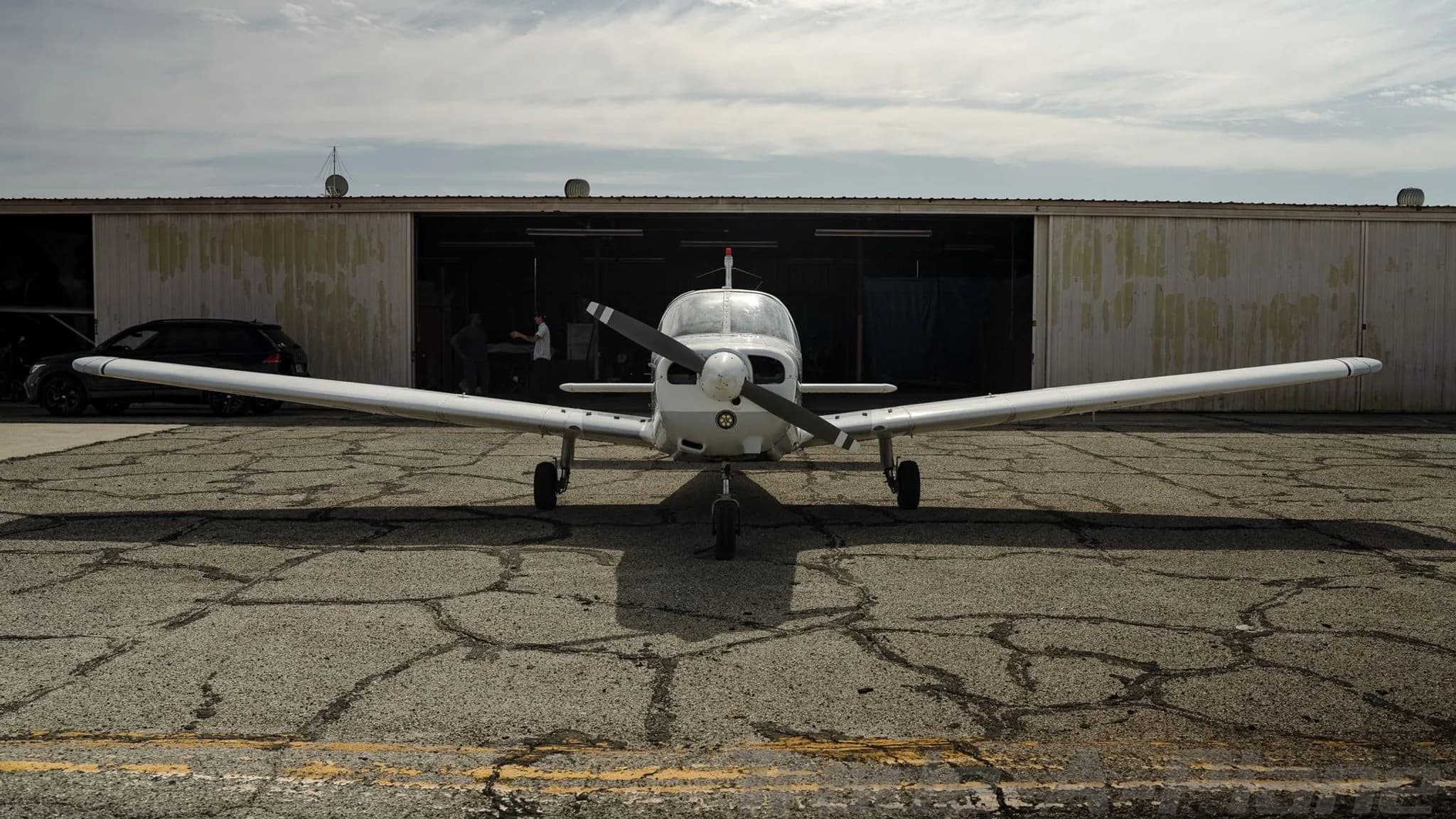 Front view of a white Piper Cherokee N41978 parked in front of an open hangar.