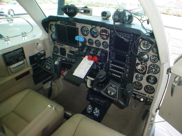 The cockpit of a Beechcraft Baron features a complex instrument panel with multiple gauges and two yokes.