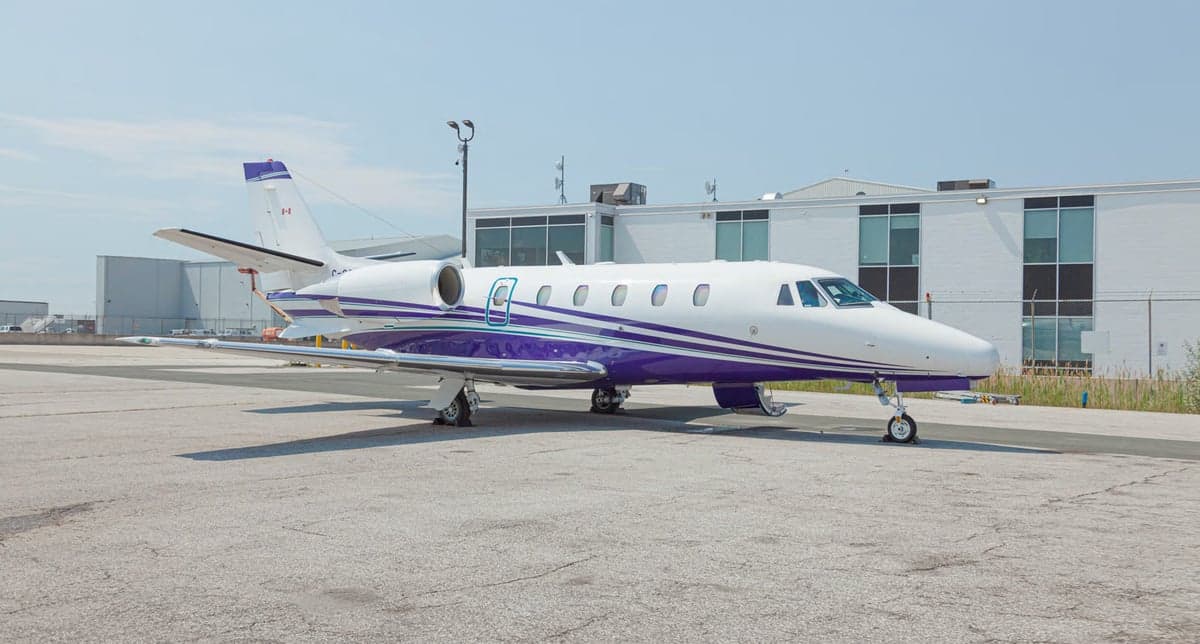 Close up of the tail and engine of a white and purple jet aircraft.