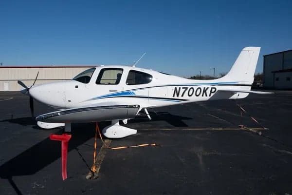Side view of a white Cirrus aircraft with blue stripe, registration N700KP.