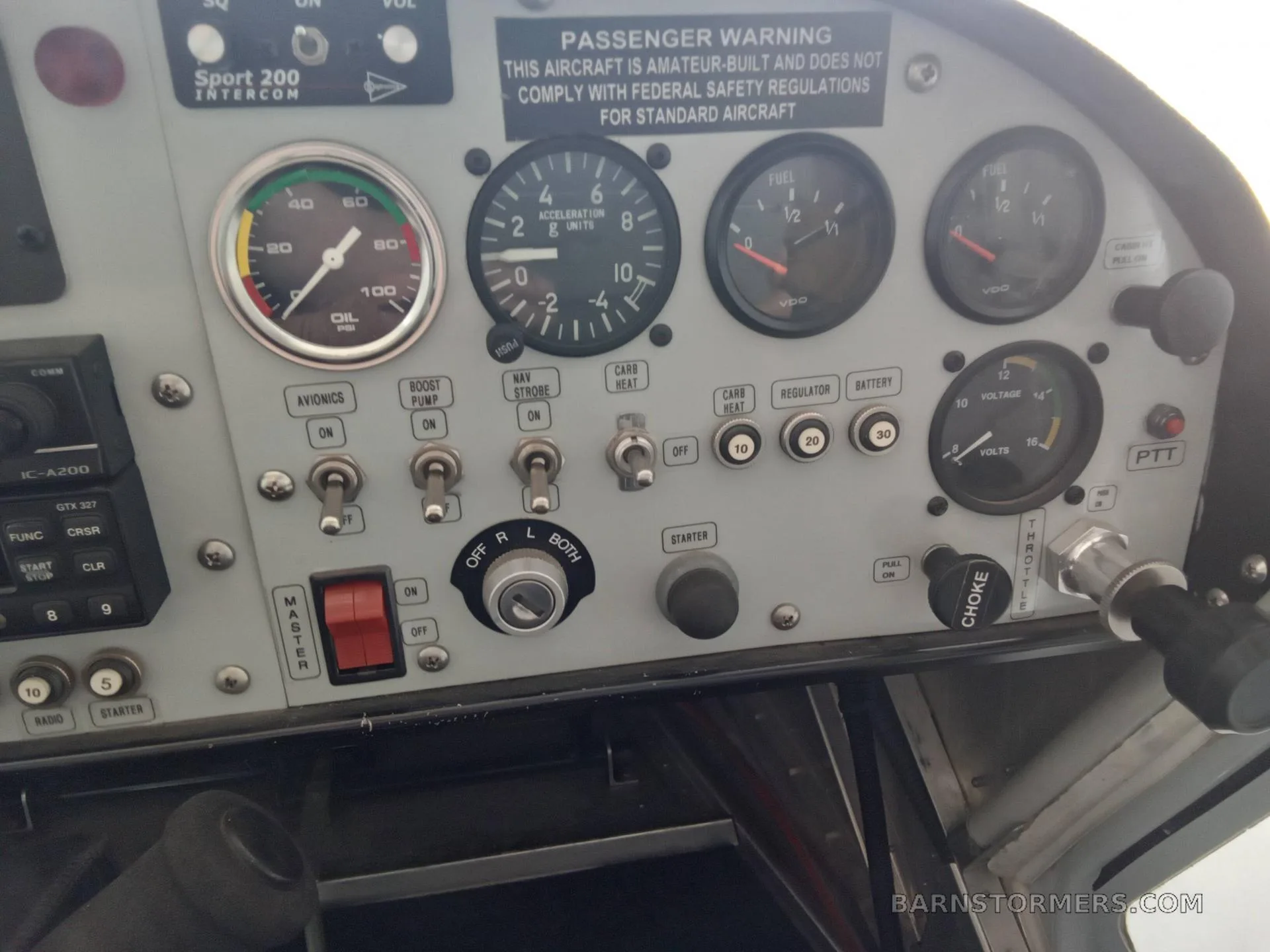 A close-up view of an aircraft's instrument panel with various gauges, switches, and a "PASSENGER WARNING" label.