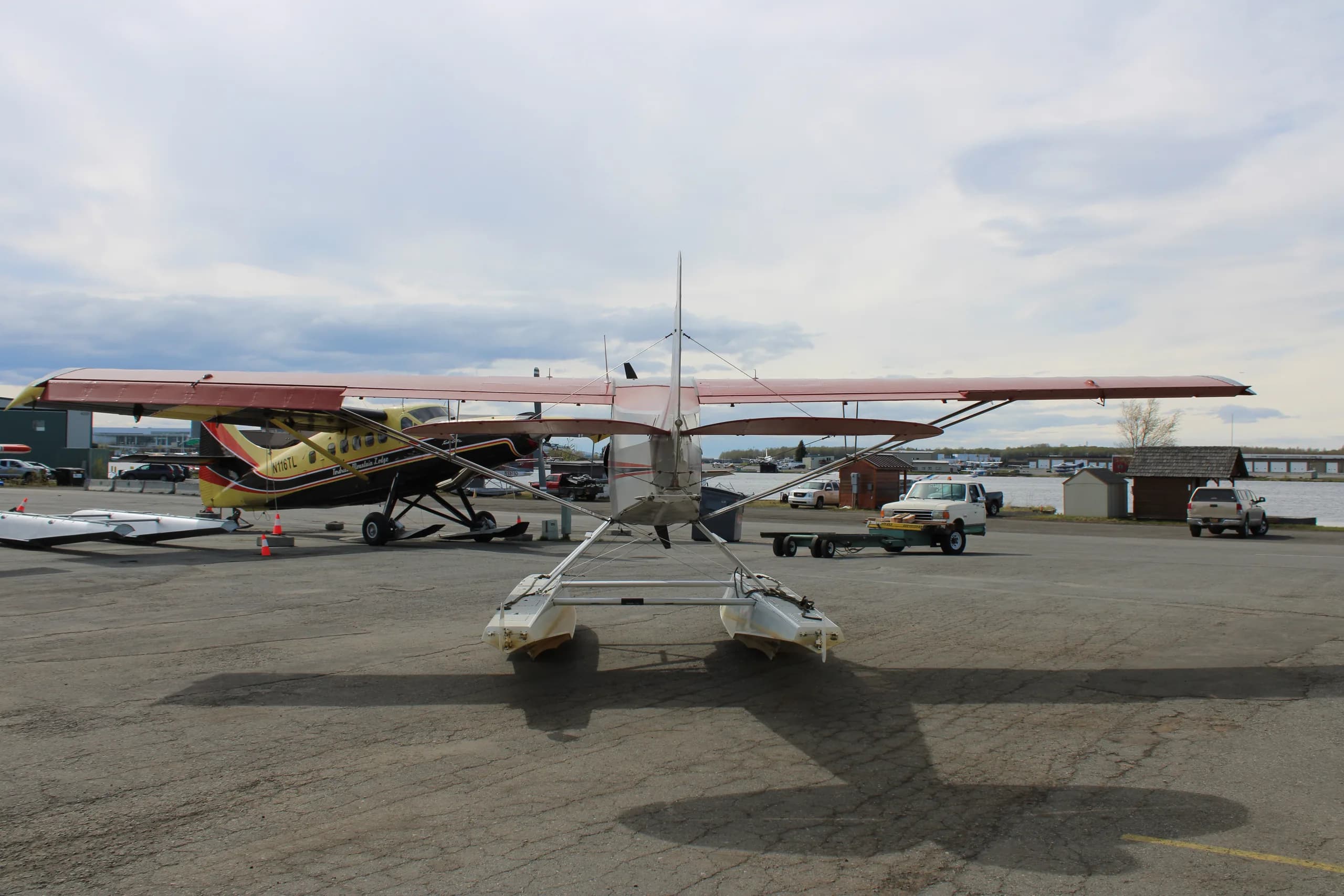 A red and silver float plane is parked on the tarmac, rear view.