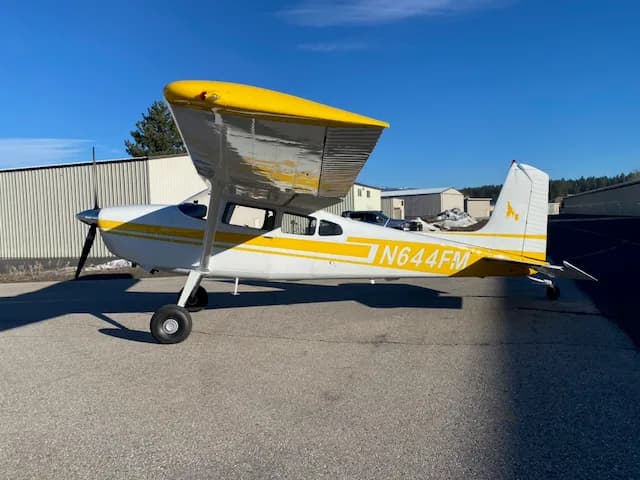 A side view of a white and yellow Cessna 172 aircraft with registration N644FM parked on a tarmac.