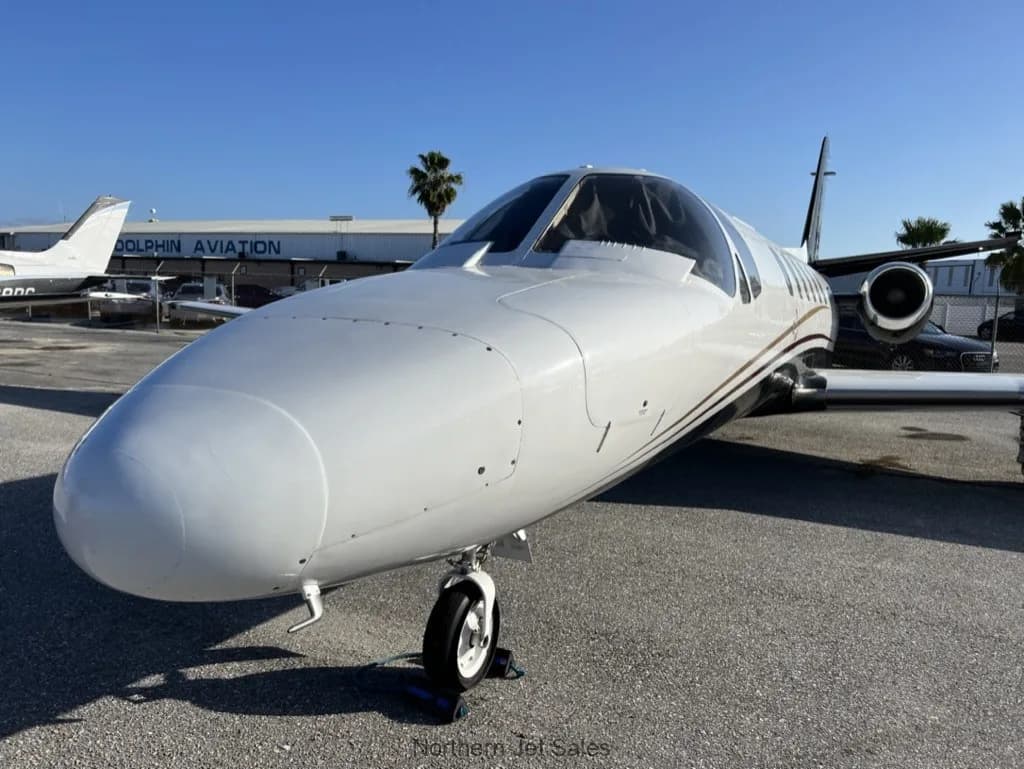 Close up of the front of a white and black jet parked on the tarmac.