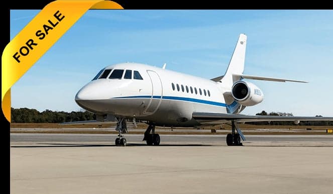 A white jet with blue stripes is parked on the tarmac with a 'FOR SALE' banner.