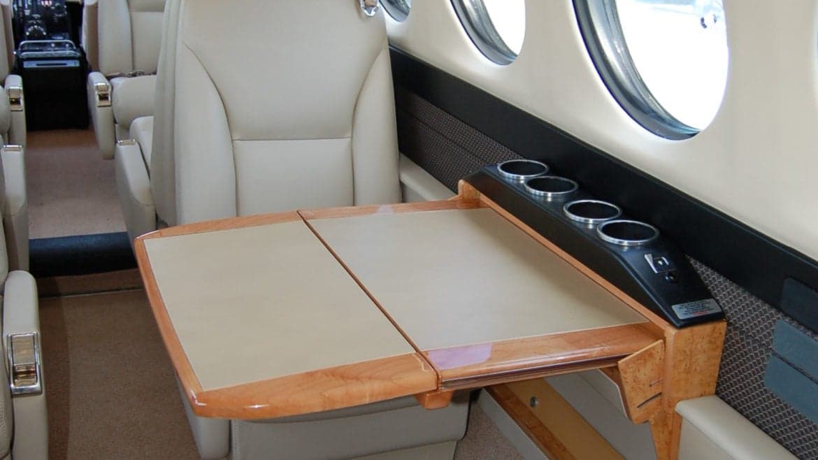 View of the aircraft's interior with a fold-out table and cup holders.