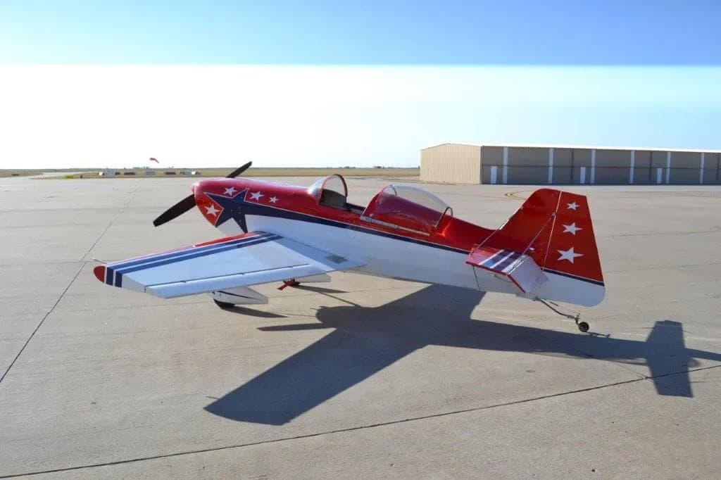 A red and white aircraft with stars on the tail and wings is parked on the tarmac.