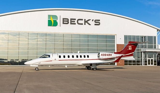 A white and red jet aircraft is parked in front of a Beck's hangar.