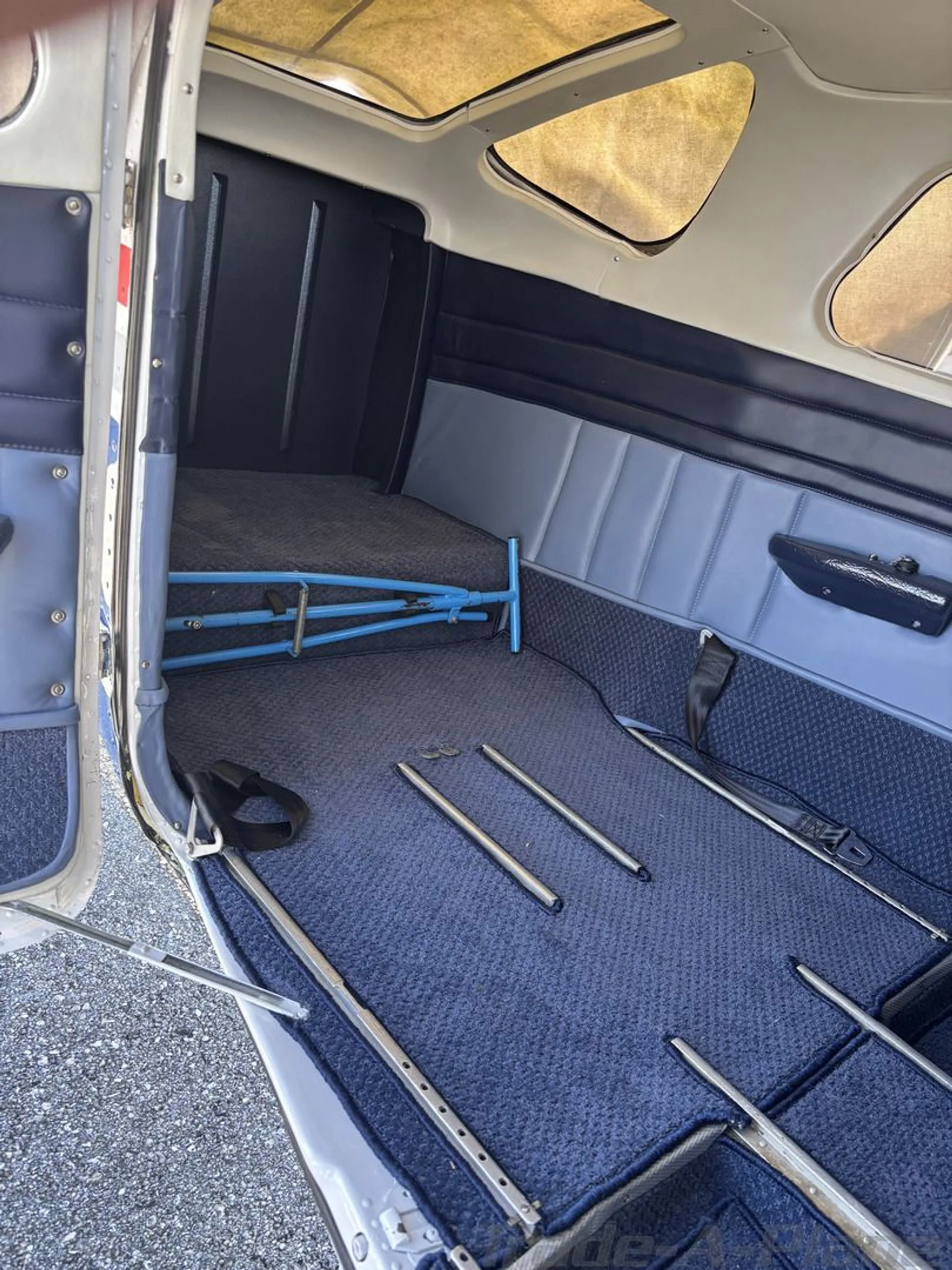 The aircraft's interior showing a blue carpeted cargo area with some equipment and no rear seats.