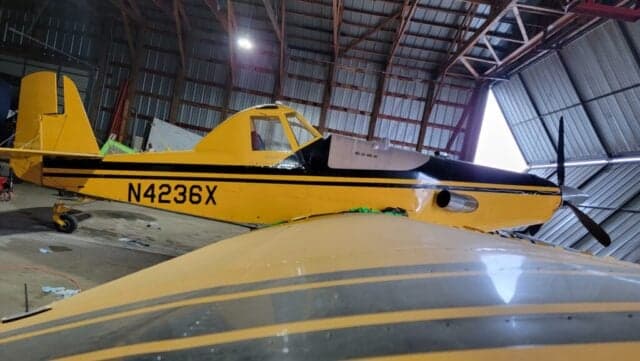 A yellow and black Air Tractor AT-400 sits inside a hangar.