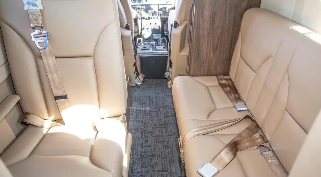 A view of the beige leather aircraft cabin seats and aisle, looking towards the cockpit.