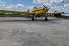 Yellow and blue agricultural aircraft parked on a concrete surface.