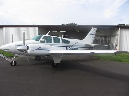 Beechcraft Bonanza N8969M parked in front of a hangar.
