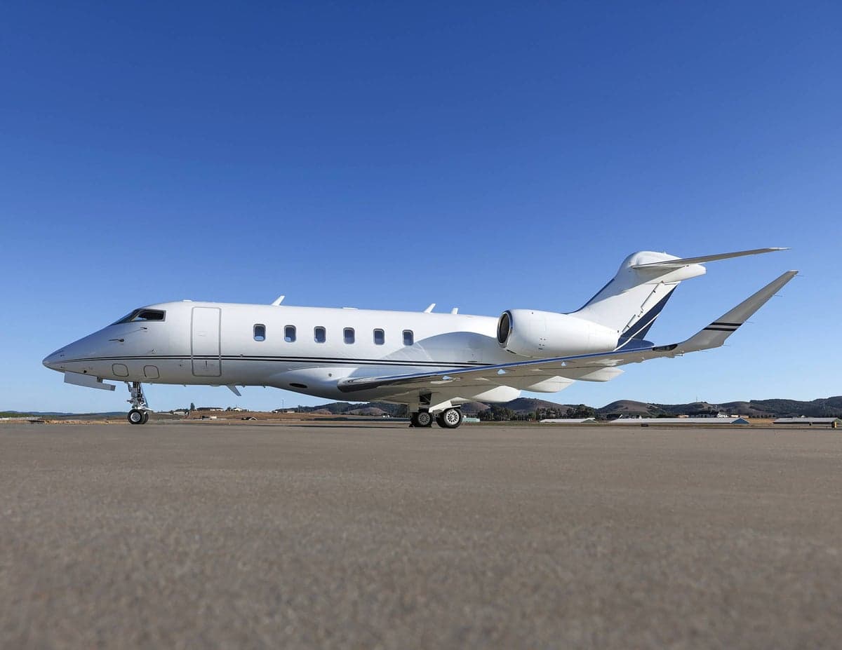 Side view of a white aircraft with blue accents parked on the tarmac.