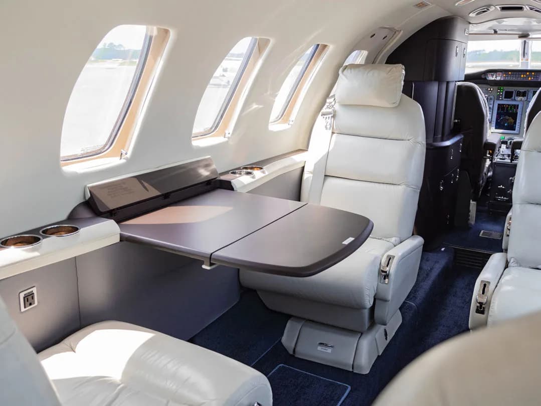 Aircraft interior with white leather seats and a table.