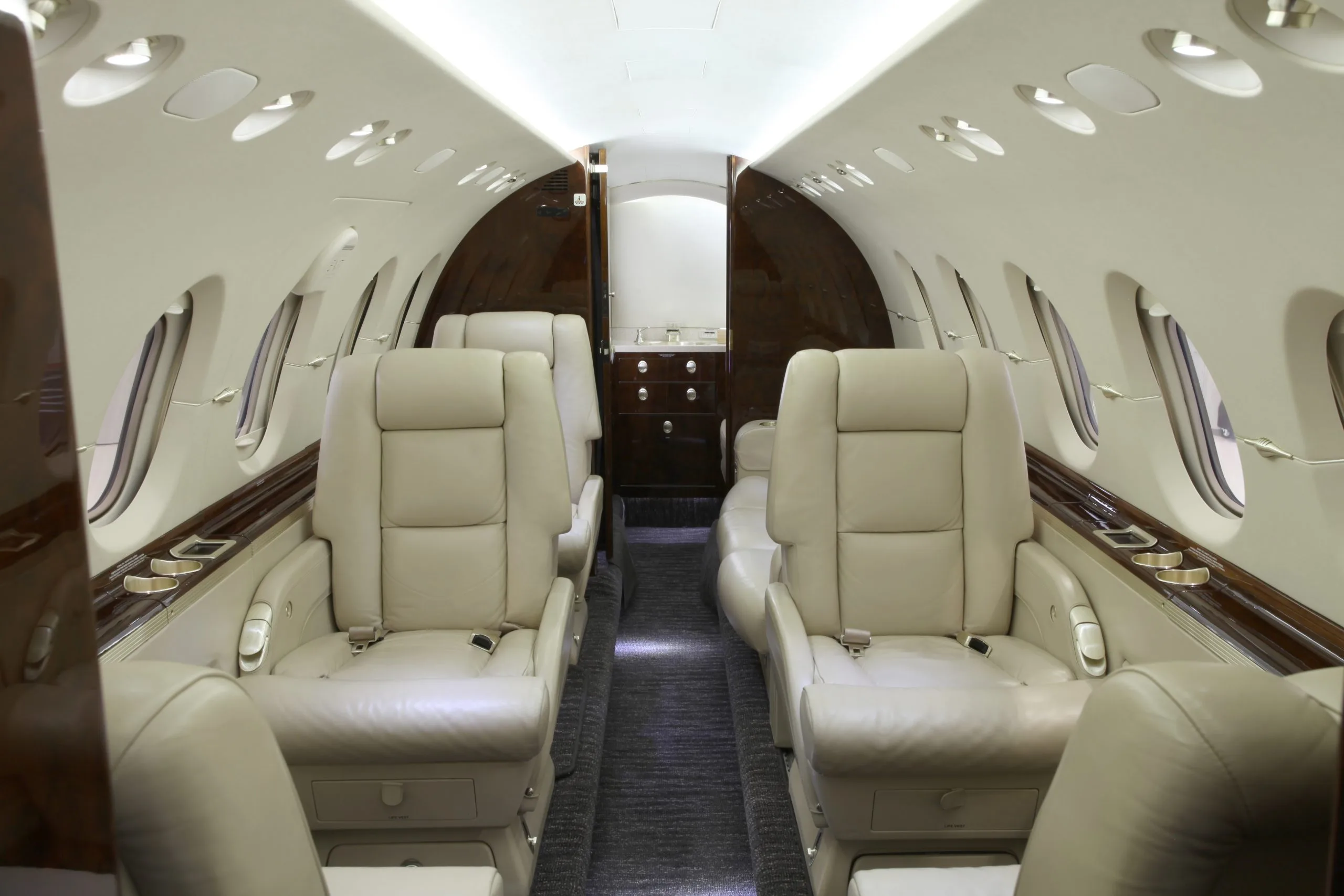 The interior of a Hawker 400XP aircraft with leather seats and wooden trim.