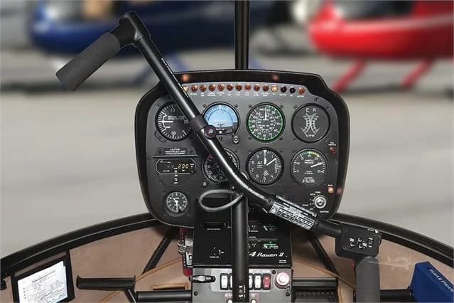 The cockpit of a Robinson R44 helicopter with analog gauges.