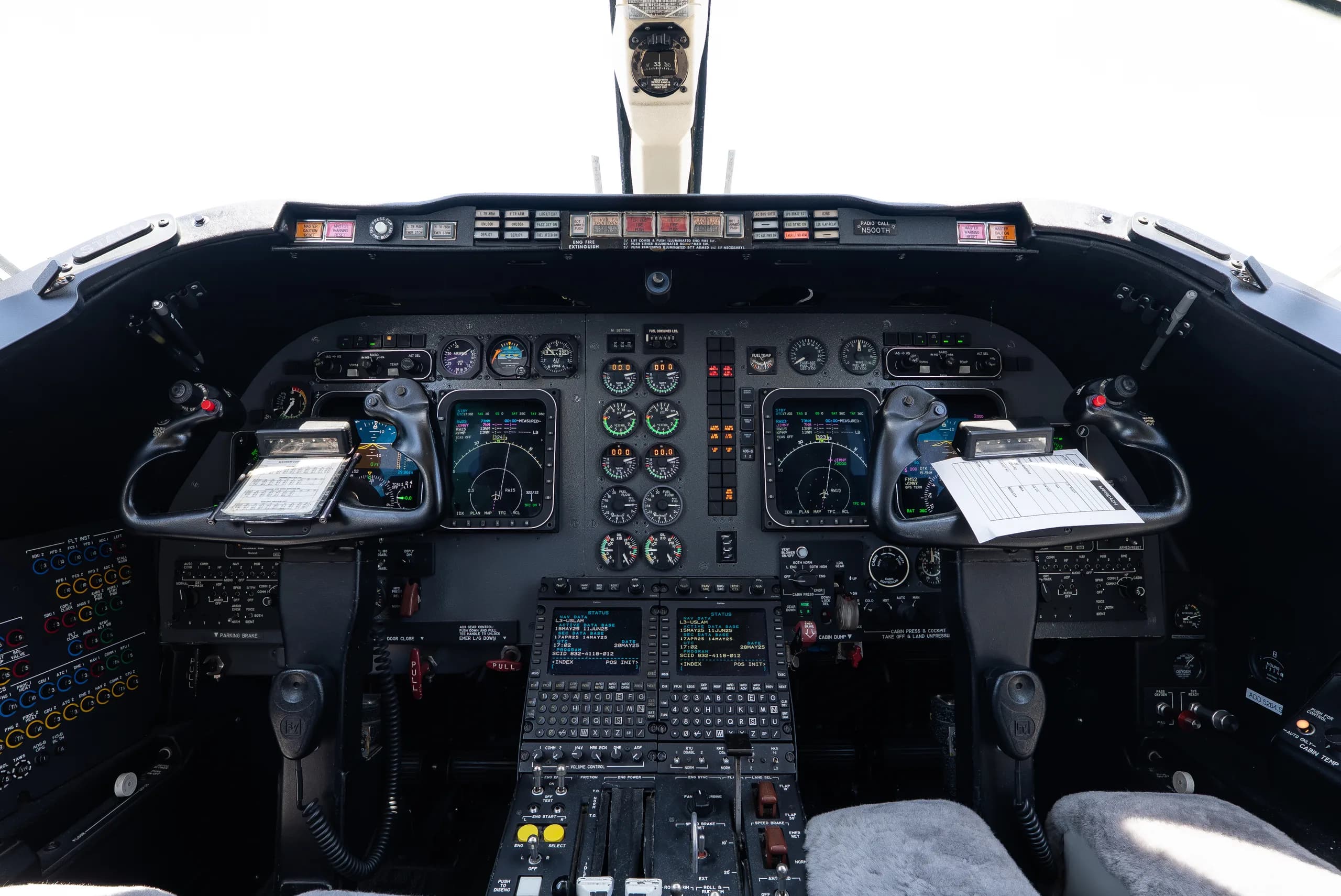 The aircraft cockpit displays a complex array of analog gauges and digital screens, with two control yokes.