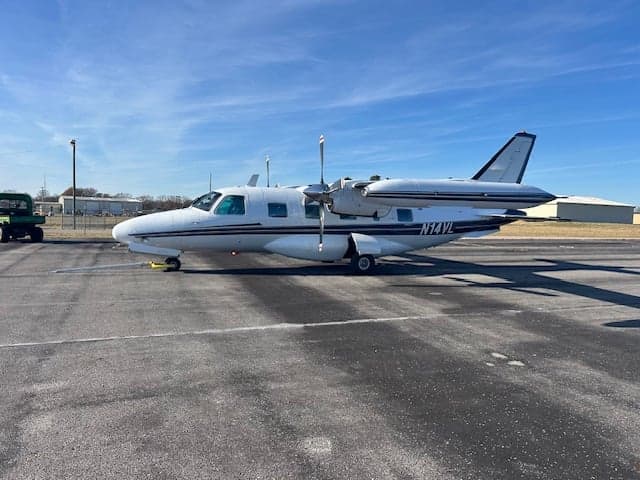 Side view of a white aircraft with black stripes on the tarmac.