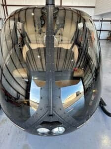 A front view of the Robinson R66 helicopter shows the reflection of the hangar.
