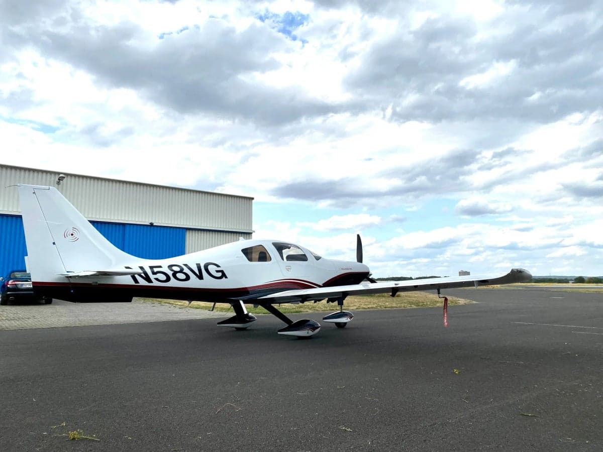Side view of Columbia 400 aircraft N58VG parked on the tarmac in front of a hangar.