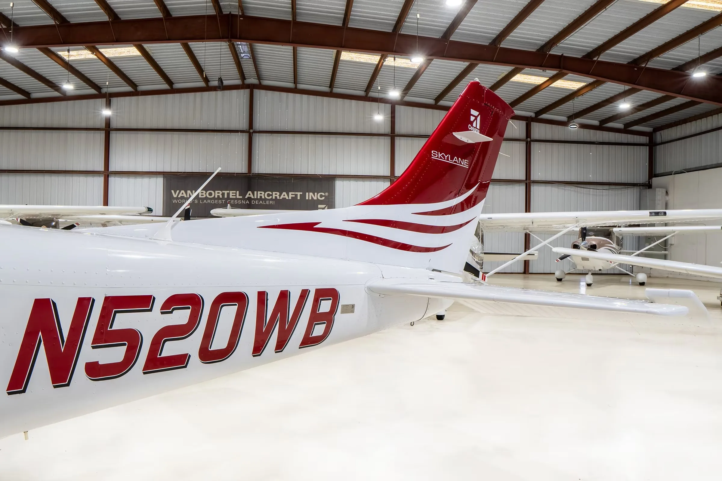 A close-up view of the tail of a white Cessna Skylane N520WB with red and grey stripes, showing the registration number.