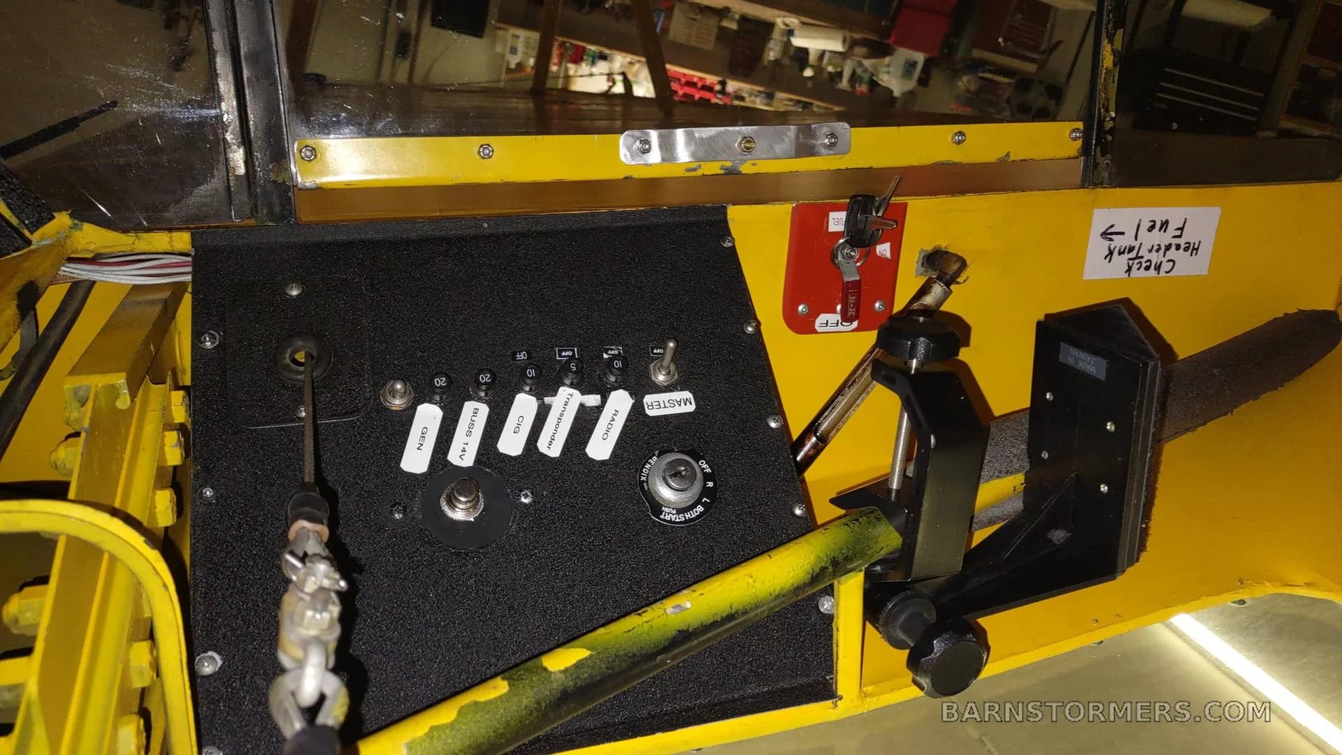 A close-up of the yellow aircraft's interior side panel with various switches and a fuel tank label.