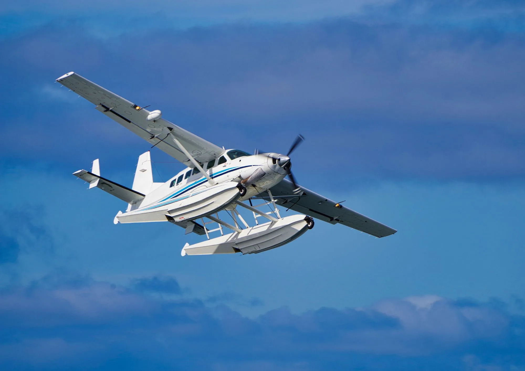 A seaplane in flight against a cloudy blue sky.
